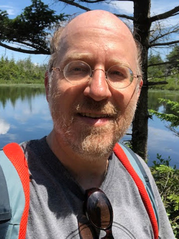 Professor Ivan Kreilkamp, pictured outdoors with a tree and a lake in the background.