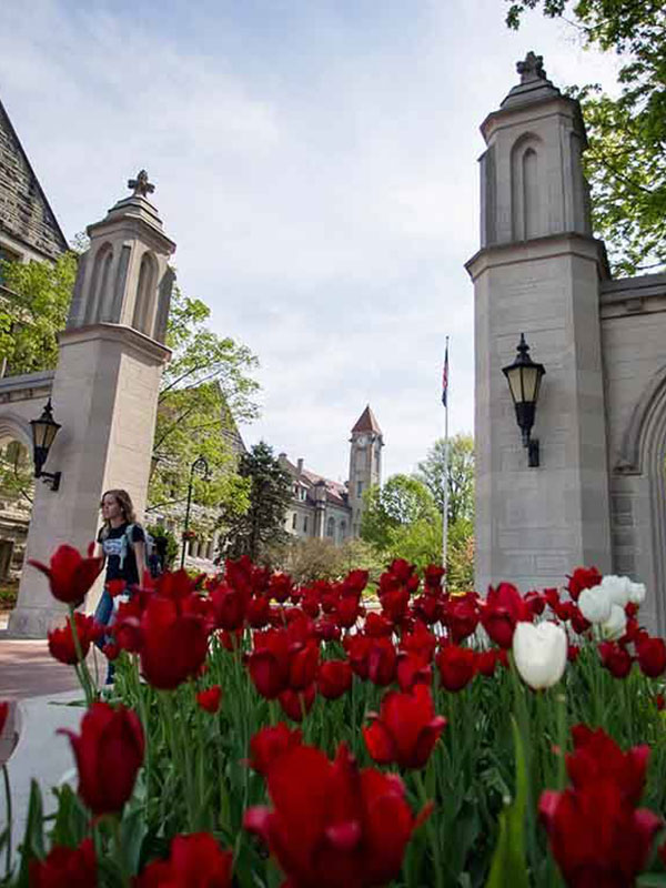 A low-angle shot of the Samples Gates, with red and white flowers in the foreground.