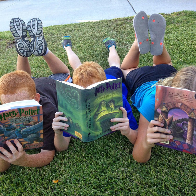 Three kids reading Harry Potter books