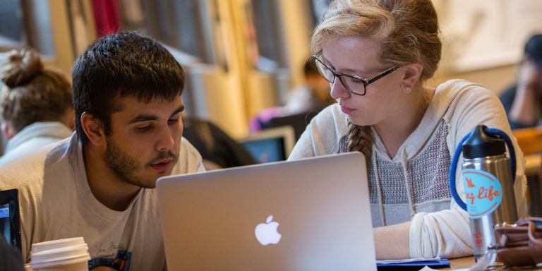 two students studying from one laptop